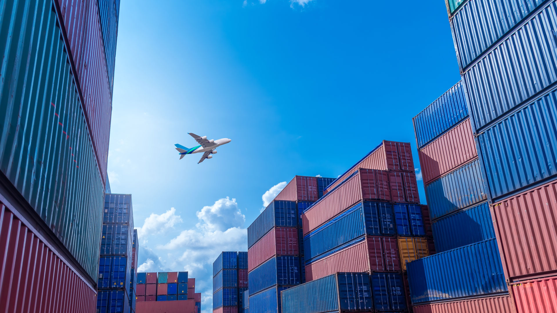 A plane flying over a cargo port, representing Jabil’s supply chain and logistics expertise in global trade and transportation.
